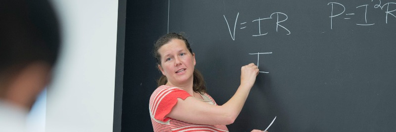 Professor Libby Bucholz teaches an undergraduate class at a chalkboard 