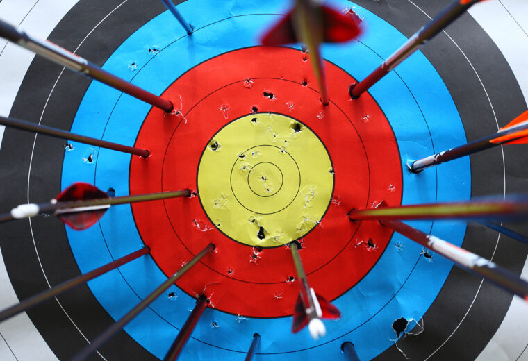 a target board with arrows stuck in everywhere but the bullseye
