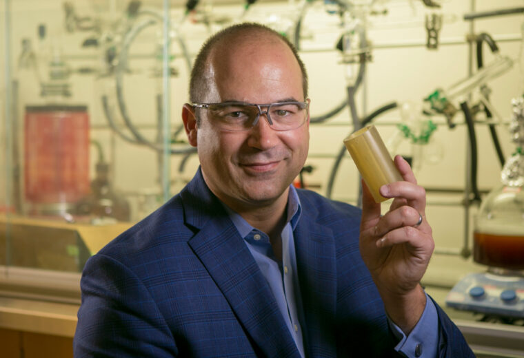 A man in a lab holding a plastic tube
