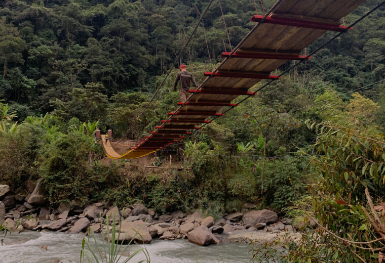 A hanging bridge over a river in a mountainous jungle area