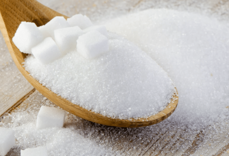 wooden spoon holding granulated and cubes of table sugar