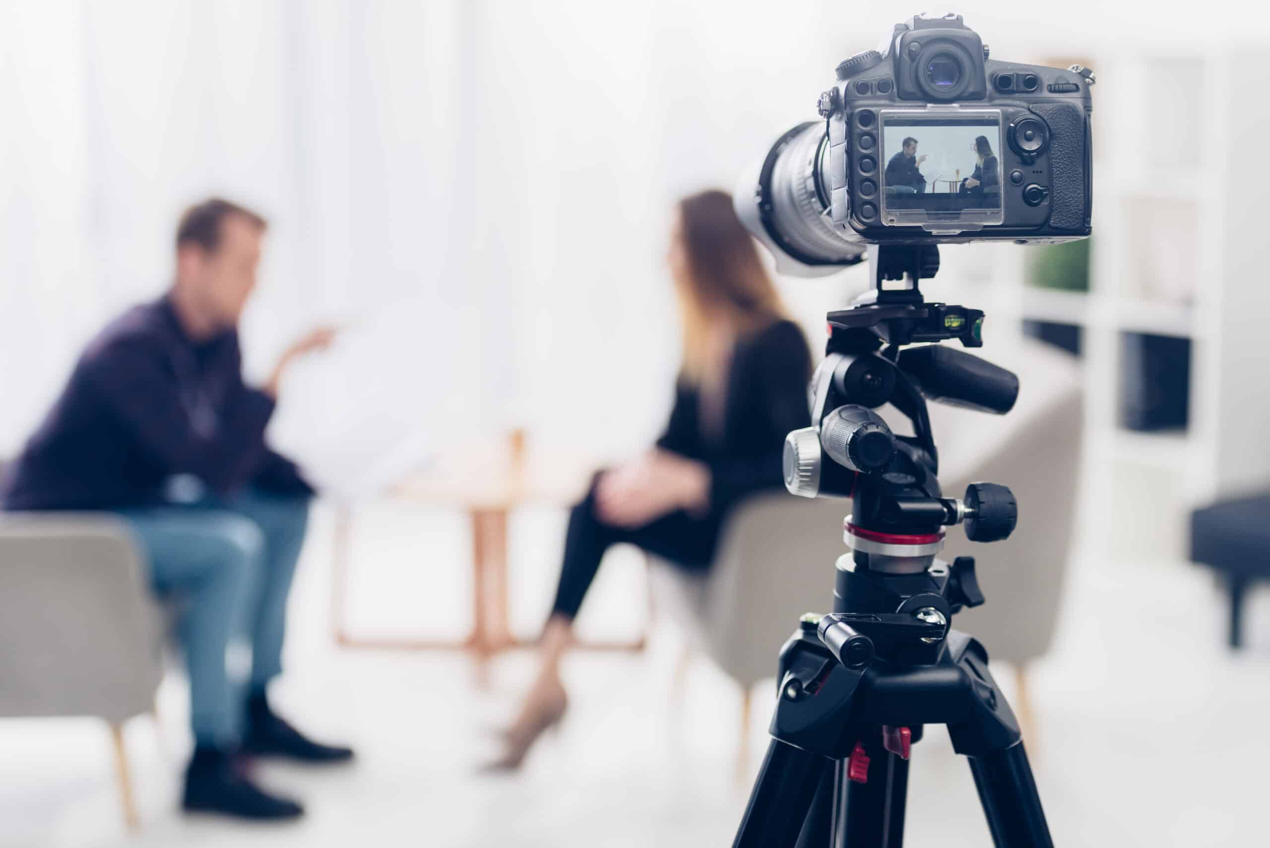 news camera on tripod woman and man seated