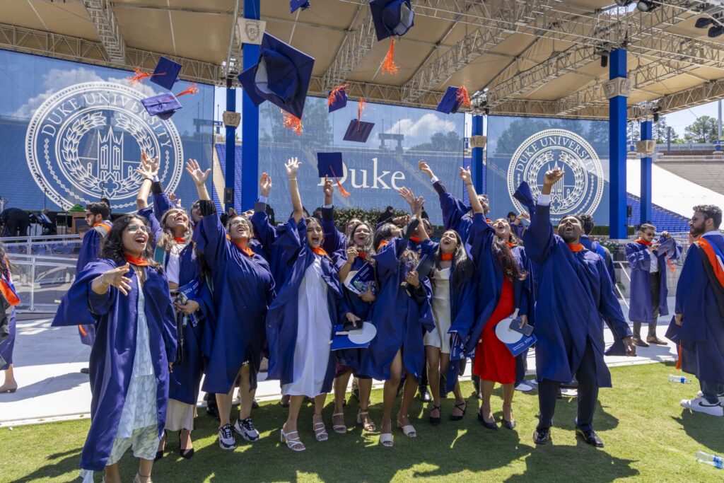 Pratt School of Engineering graduates toss their caps in the air at Wallace Wade Stadium