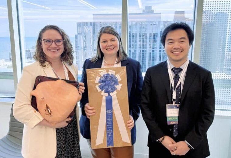 three students standing with a plaque and ribbon